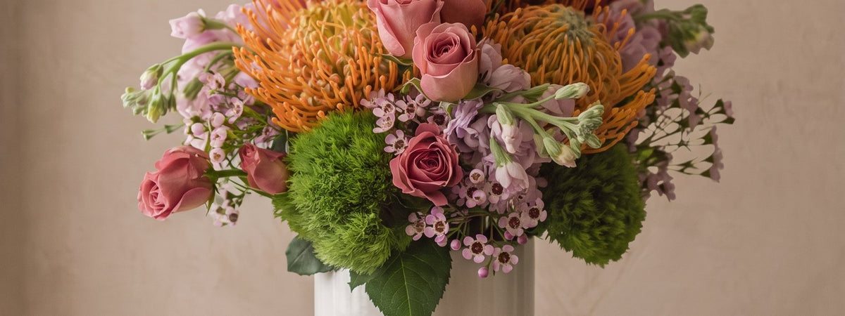 Pincushion protea, roses and green hydrangea across the studio backdrop