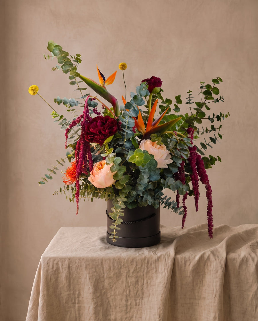 Fragrant Beauty: bird of paradise, eucalyptus and garden rose in a dark vessel