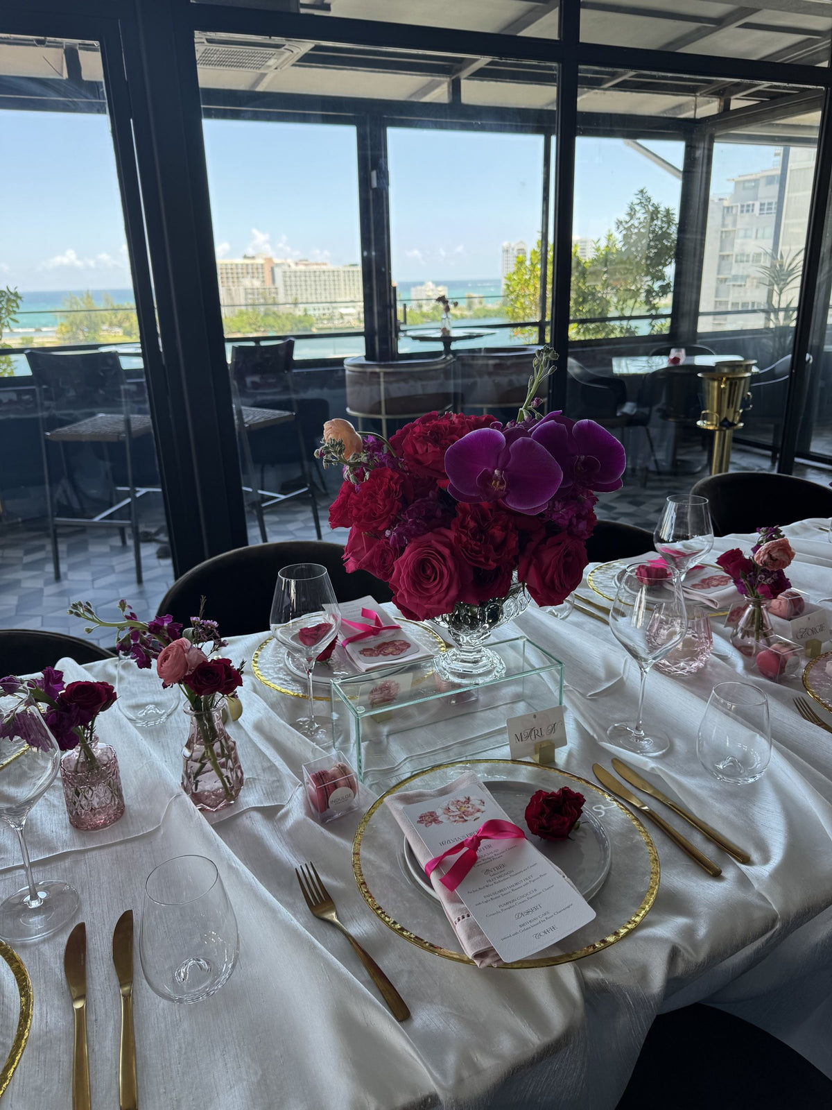 Purple orchids and red roses on a long table with a view of the sea