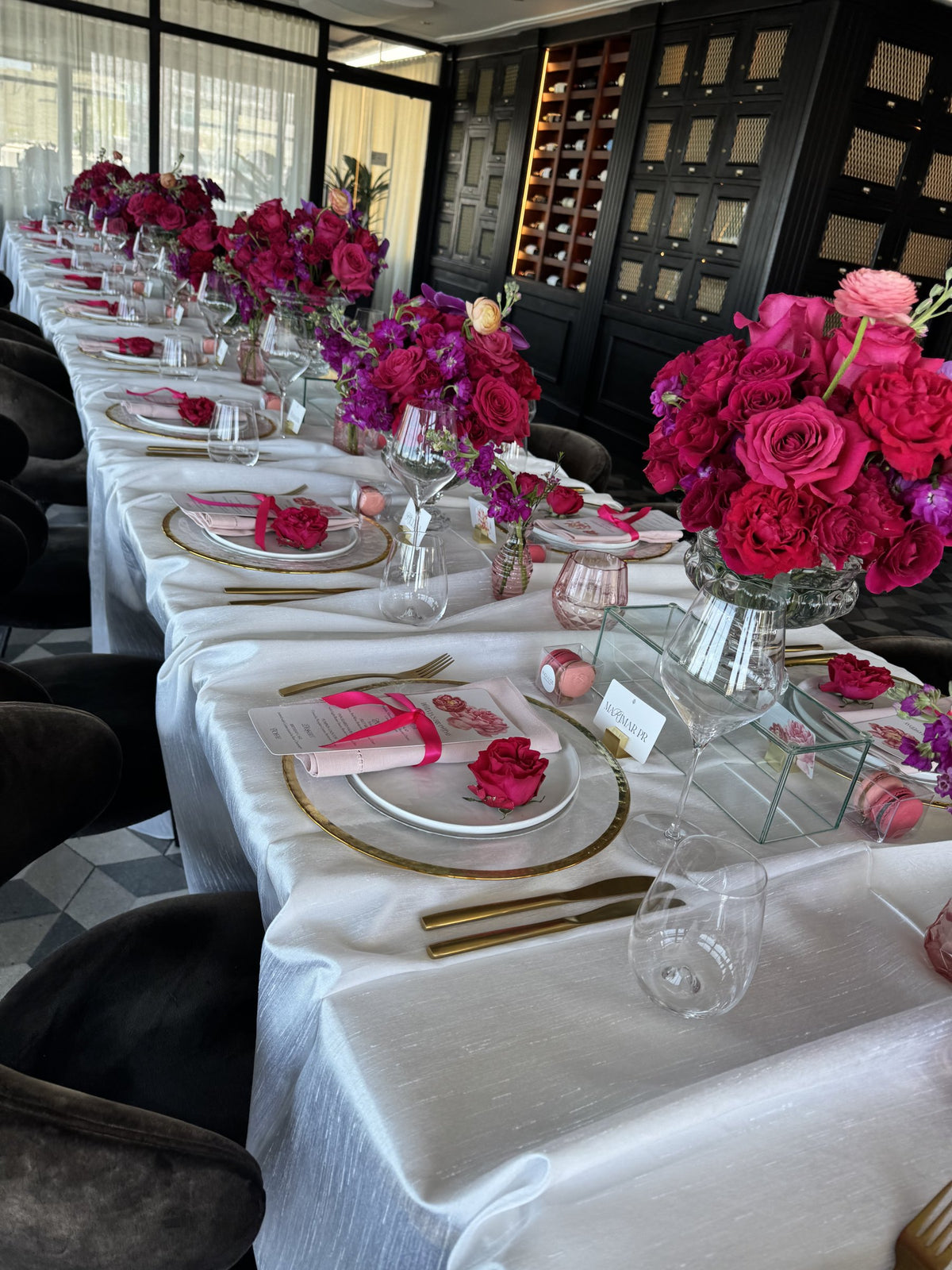 Long table with fuchsia arrangements and gold-rimmed chargers