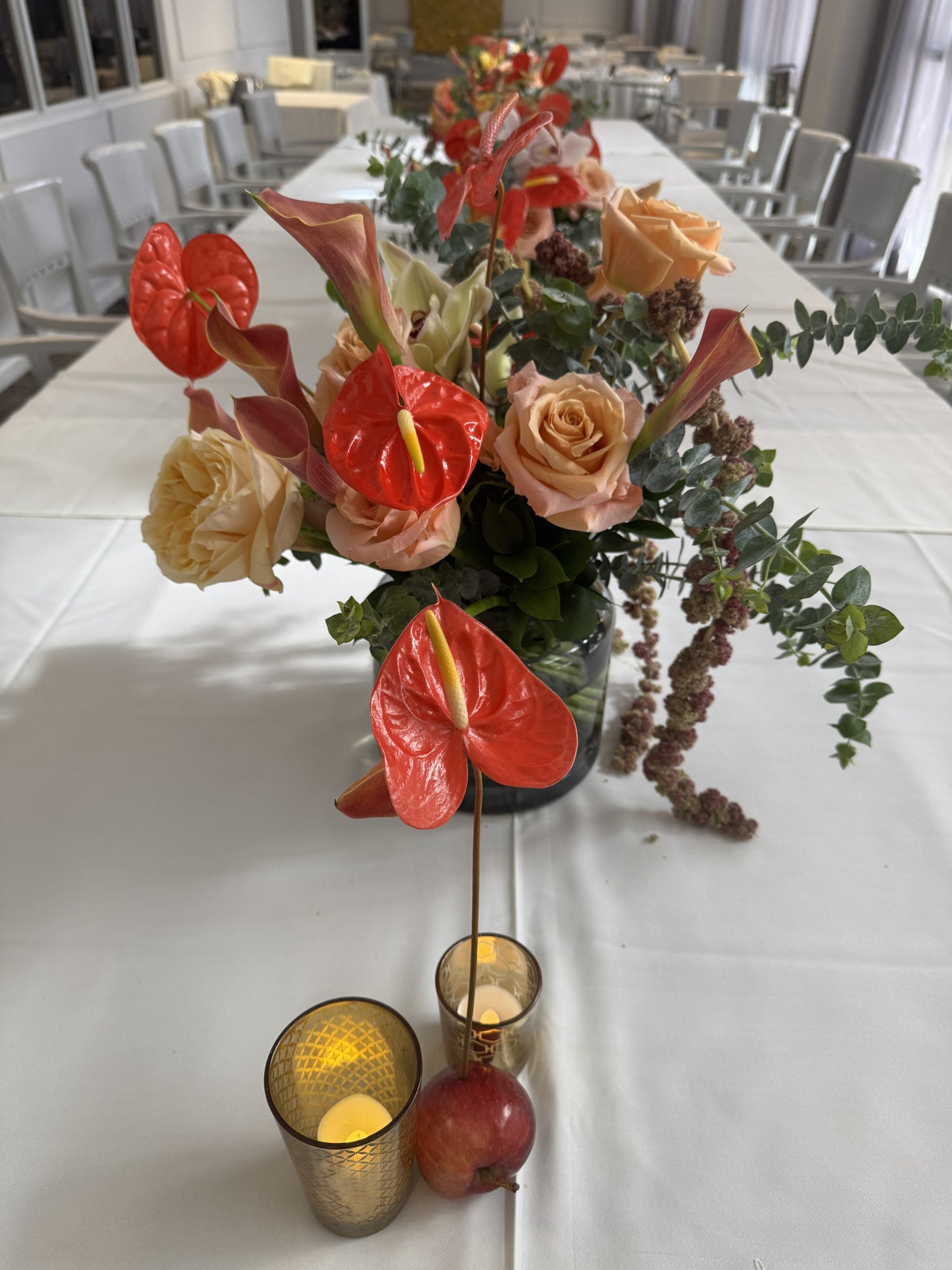 Close-up of red anthurium and peach roses with eucalyptus