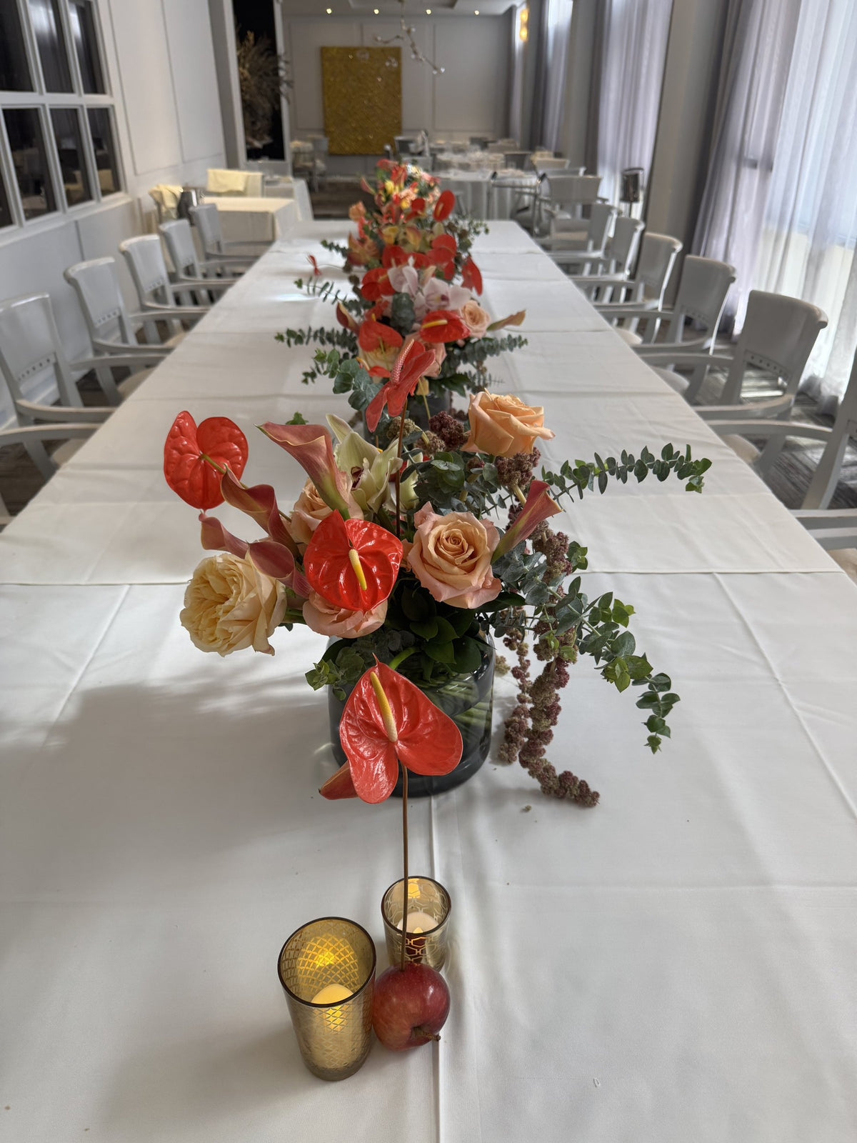Long table with a row of anthurium and rose arrangements