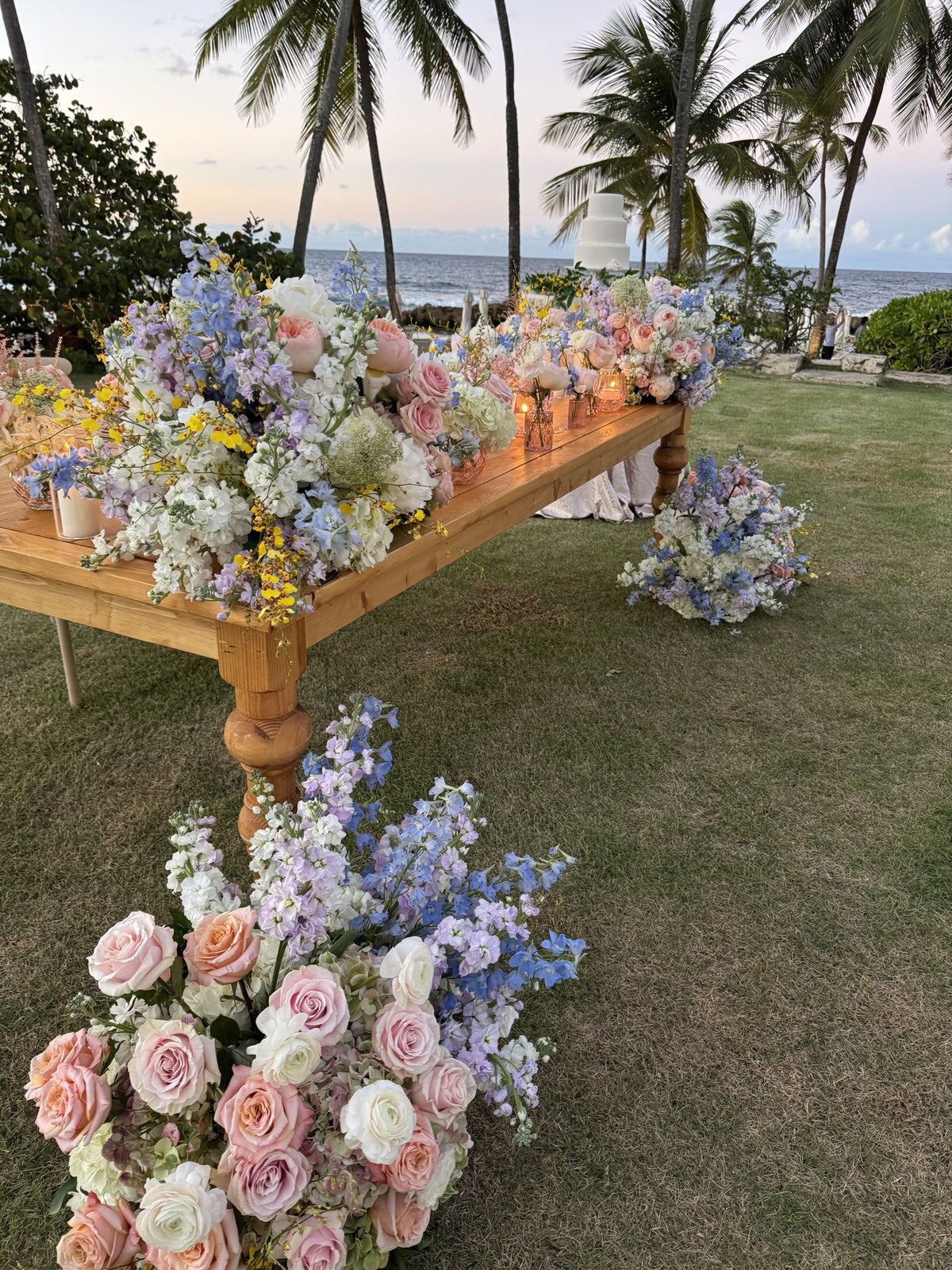 Wooden head table and a floor arrangement of pastel roses, delphinium and hydrangea