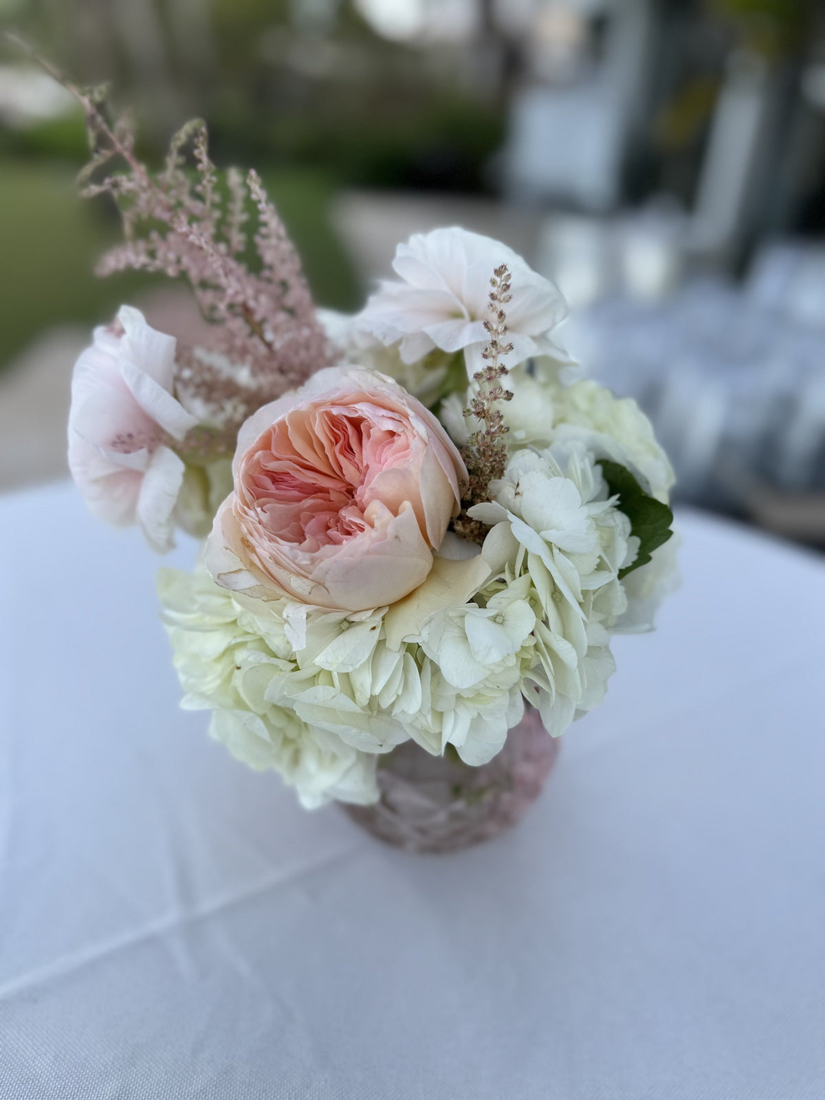 Small centerpiece of a peach garden rose with white hydrangea
