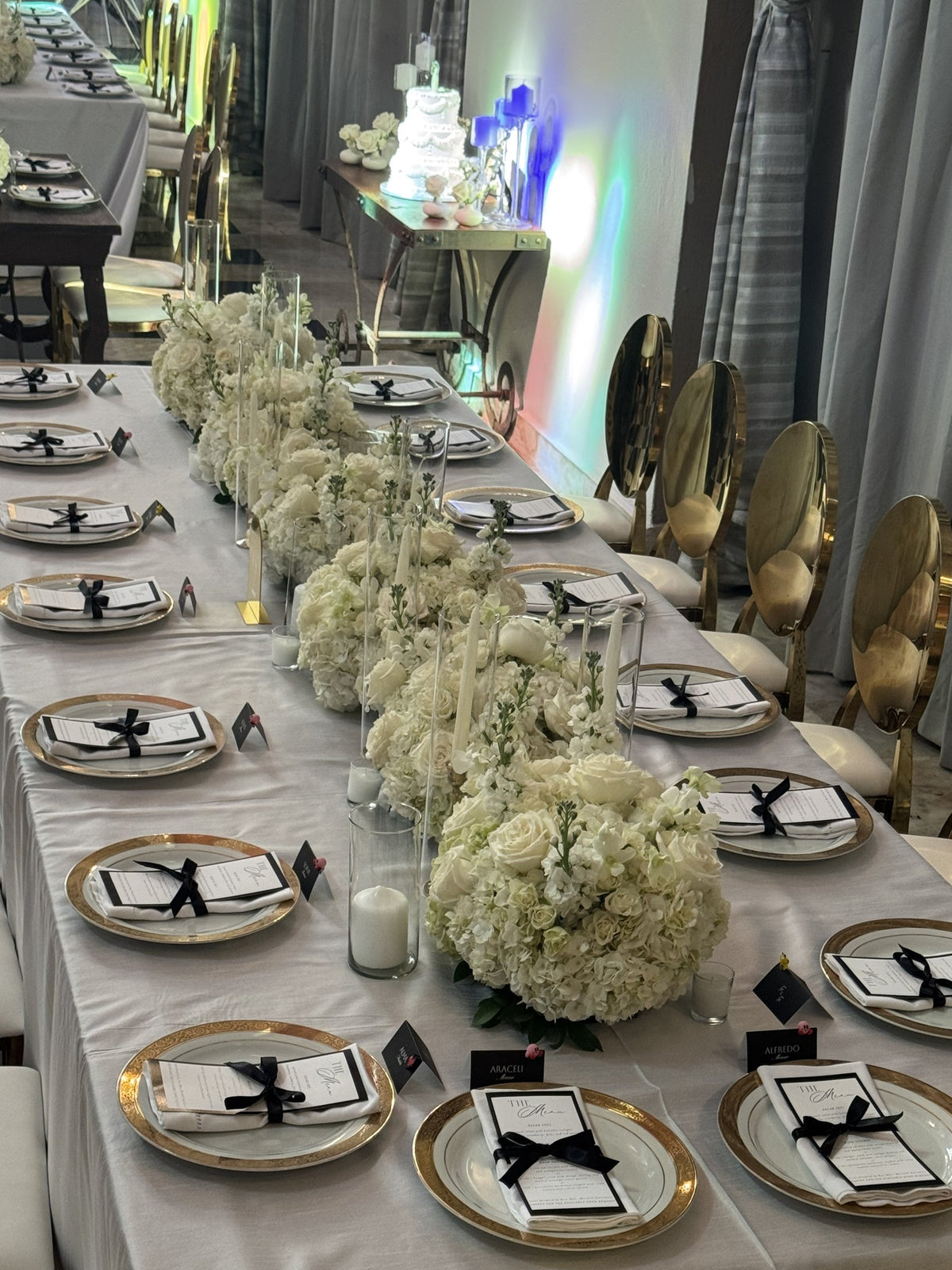 Imperial table with a run of white roses and hydrangea, gold chairs and gold-rimmed plates