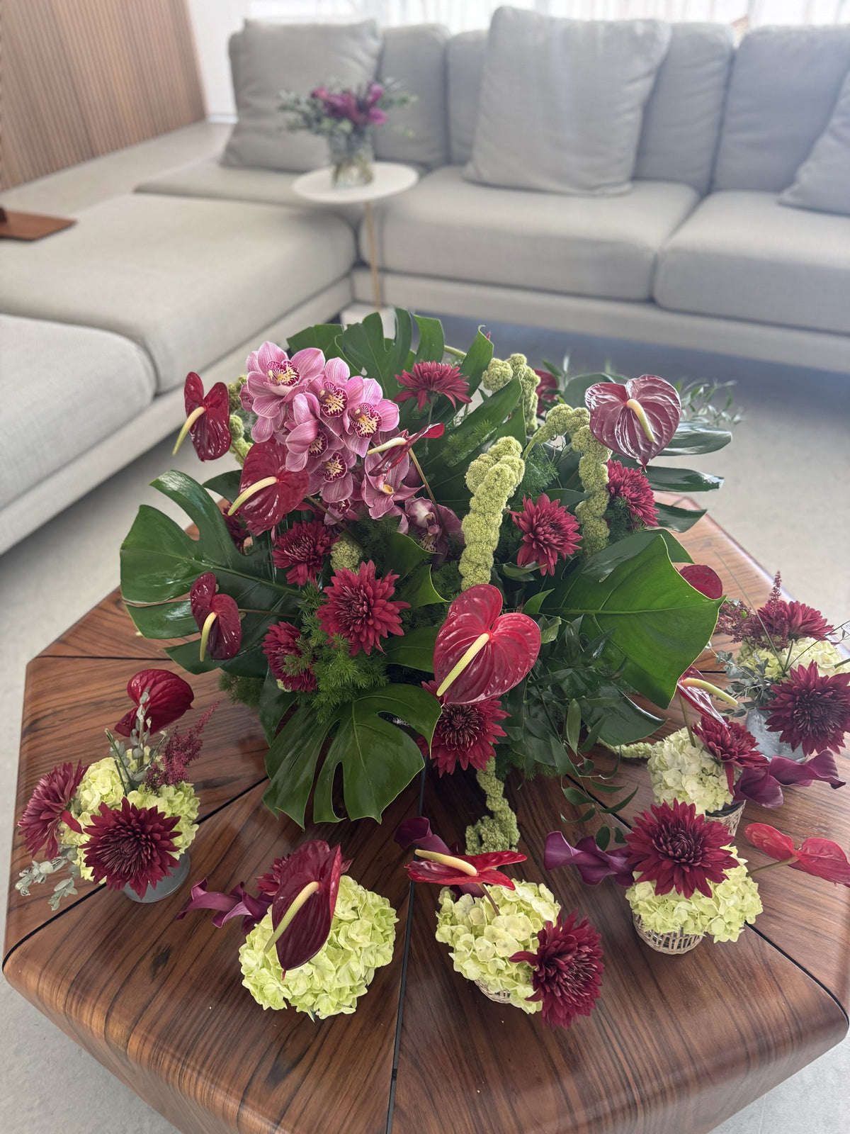 Low centerpiece of anthurium, dahlias and monstera in a living room