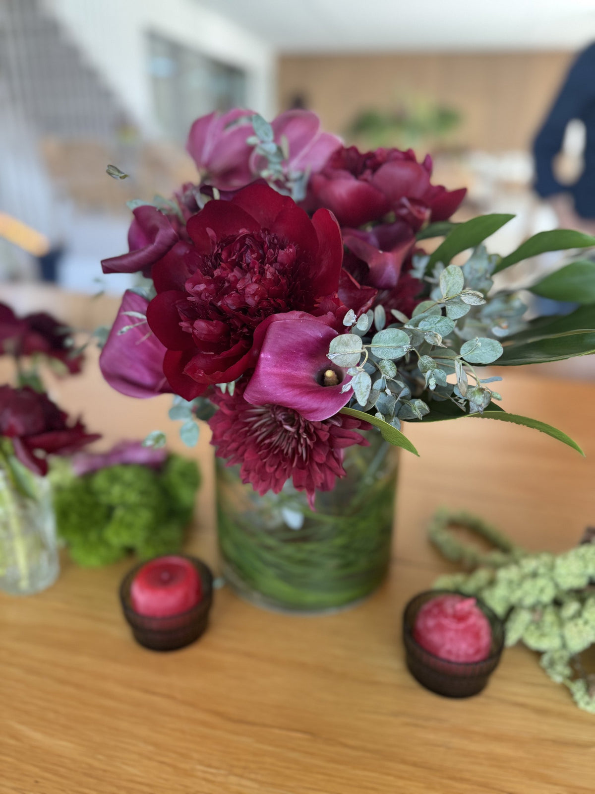 Close-up of burgundy peonies and magenta calla lilies with eucalyptus