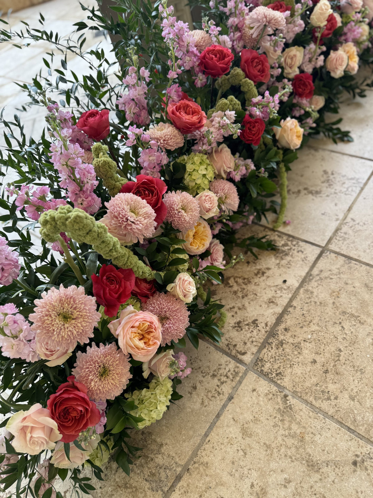 Floor garland of pink roses, dahlias, peonies and greenery along a tiled terrace