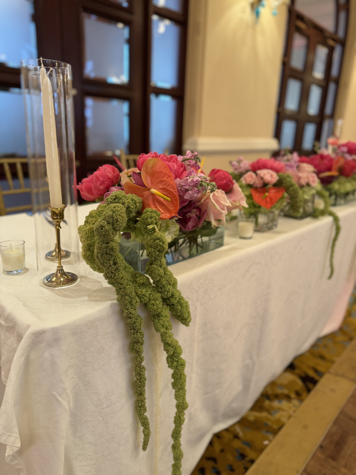 Head table with coral flowers and cascading green amaranth