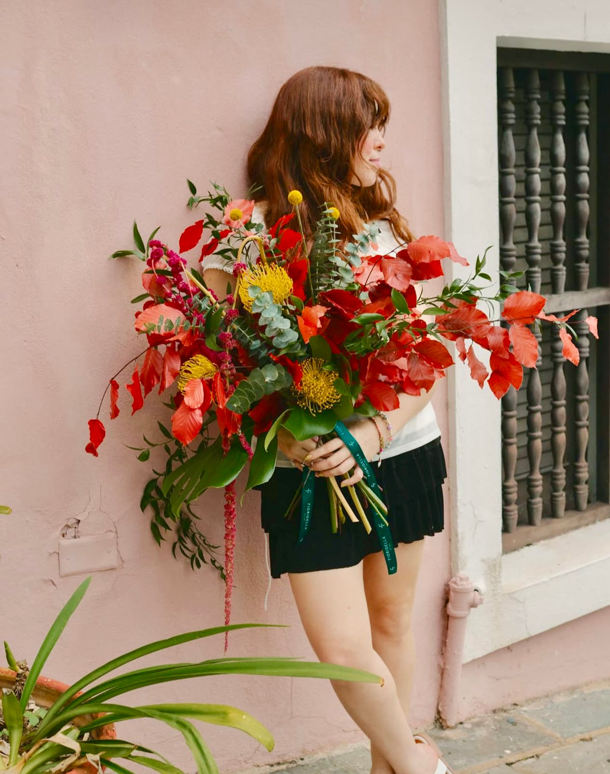 Autumn bouquet of red foliage, pincushion protea and eucalyptus against a pink wall in Old San Juan