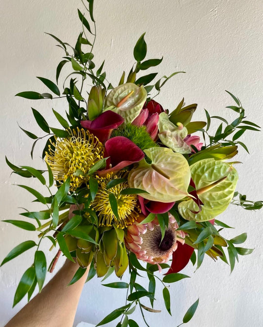 Tropicaleo hand-tied bouquet of tropical flowers and greenery in green, yellow and burgundy