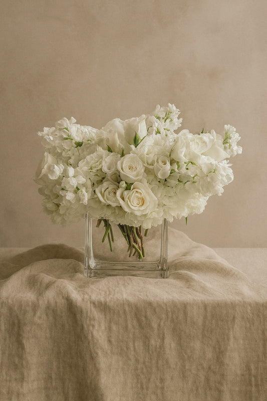 White Blooms arrangement of white hydrangea, spray roses and stock in a square crystal vase